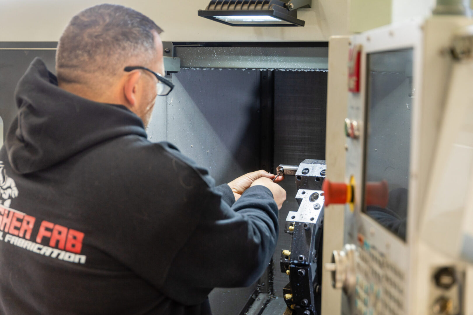 A person from Fisher Fab Metal Fabrication operating a machining and fabrication device